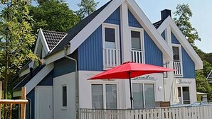 Un edificio a due piani con un portico bianco e un ombrello rosso.
