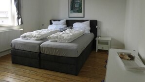 A bedroom with a bed, a bedside table, a nightstand, a window with curtains, and a framed picture on the wall. - Freundlich eingerichtete Wohnung mit Meerblick by Interhome (Dahme)