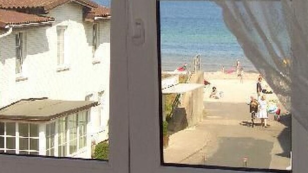 A window with a view of a beach and a building with a tiled roof. - Freundlich eingerichtete Wohnung mit Meerblick by Interhome (Dahme)