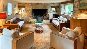 A cozy living room with a stone fireplace, comfortable seating, and a view of the outdoors. - 5 bedroom amazing home in Combrit - St Marine (Combrit - St Marine)