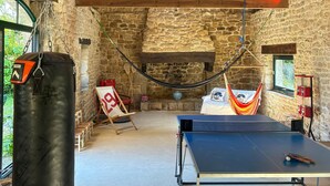 A room with a ping pong table, a hammock, a punching bag, and a stone wall. - 5 bedroom amazing home in Combrit - St Marine (Combrit - St Marine)