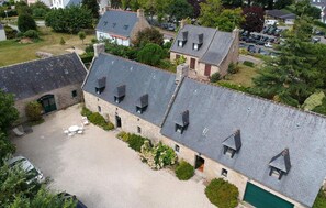 Ein Steinhaus mit mehreren Dachgeschossen und einem Kieshof.