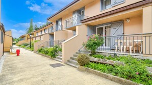 Une rangée d’immeubles d’appartements de couleur beige, dotés de balcons, un hydrant rouge et des plantes vertes.