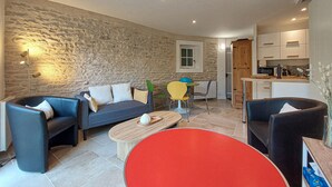 Un salon avec un mur en pierre, un canapé, une table basse et un fauteuil rouge.