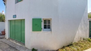 Un bâtiment blanc avec une petite fenêtre et des volets verts.