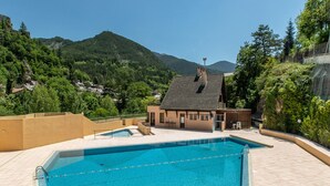 Piscina com vista para montanhas e um edifício com telhado inclinado.