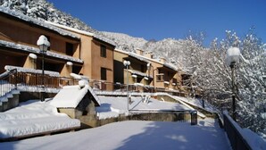 Um edifício coberto de neve com varandas, uma escadaria e um caminho também coberto de neve.