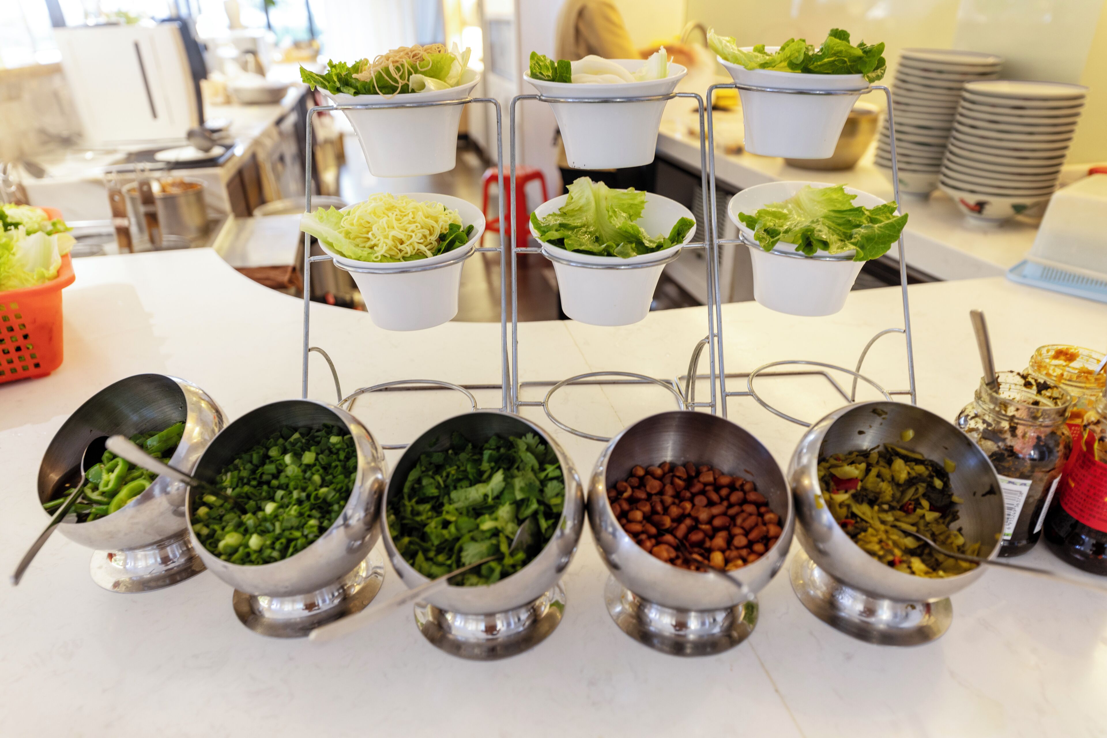 A buffet setup with various food items in metal bowls and white cups.