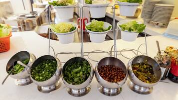 A buffet setup with various food items in metal bowls and white cups.