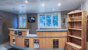 A reception desk with a TV, a window with a view of snow-covered trees, and a wooden bookshelf.