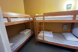 Huone, jossa on kerrossängyt, seinäpistorasia ja valokatkaisin.