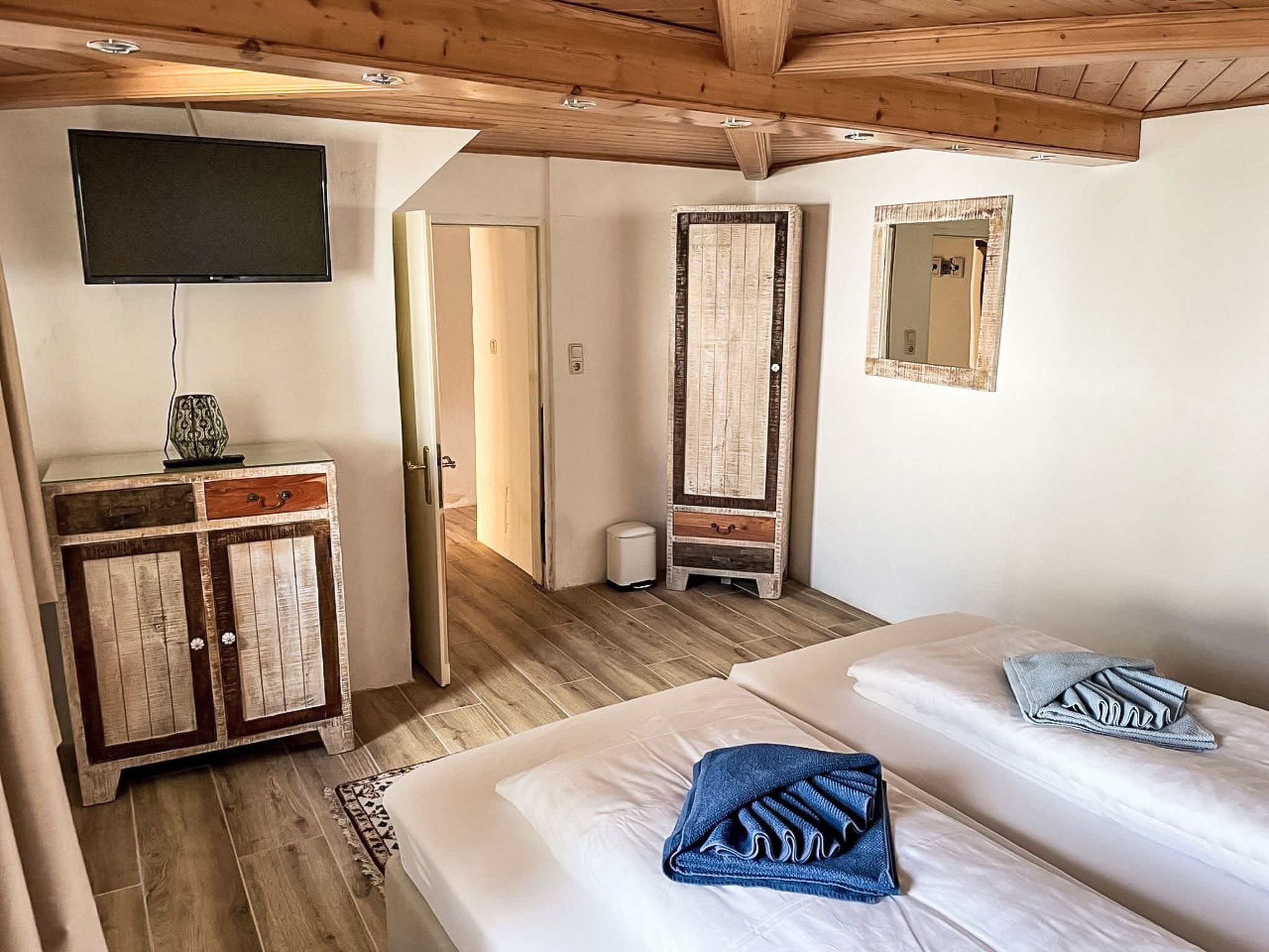 A room with two beds, a television, a wardrobe, and a mirror.