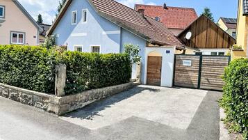 A residential building with a sloped roof, a gated entrance, and a well-maintained hedge.