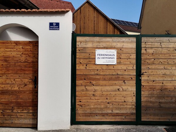Une porte en bois avec une pancarte indiquant « FERIENHAUS zu vermieten » et un panneau indiquant le numéro de la maison : « 9 Schulgasse Casa Domingo ».
