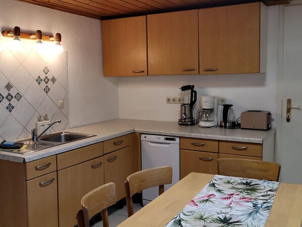 Una cocina compacta con armarios de madera, lavavajillas, cafetera y tostadora.