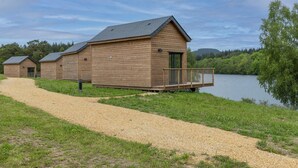 A wooden cabin with a deck, a gravel path, and a lake view. - Cabin near Meyrignac Lake (MEYRIGNAC  L'EGLISE)