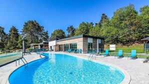 Una piscina con sillas de descanso y un edificio con ventanas amplias.