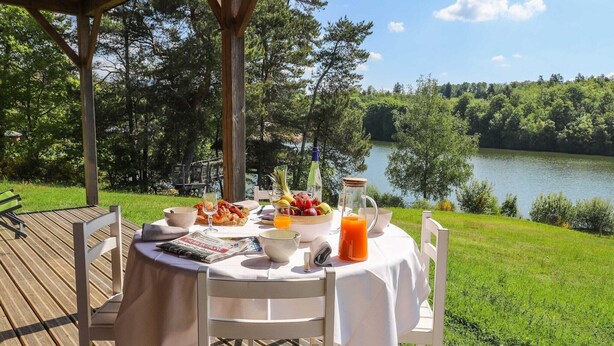 Mesa al aire libre con vista a un lago, rodeada de vegetación.