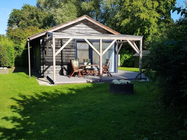 Une cabane en bois dotée d’un patio couvert, d’une table et de chaises.