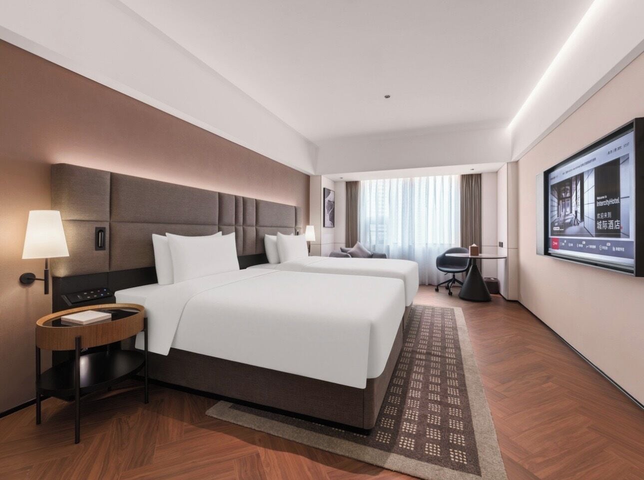 A hotel room with two beds, a desk, a chair, a TV, and a window with curtains.