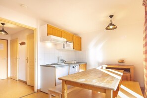 Una cocina compacta con microondas, cafetera y armarios de madera.