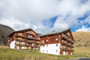 A wooden chalet with multiple balconies, set against a mountainous backdrop. - Comfortable apartment with pool access (SAINT-SORLIN-D'ARVES)