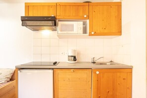 A compact kitchen with wooden cabinets, a microwave, a coffee maker, and a dishwasher. - Comfortable apartment with pool access (SAINT-SORLIN-D'ARVES)
