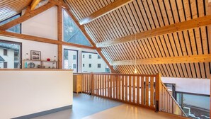 A spacious attic room with a sloped wooden ceiling, large windows, and a view of buildings outside. - Mountain Lodging with Private Balcony (Saint  Colomban  des  Villards)