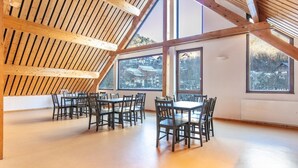 A spacious room with high ceilings and large windows, featuring a wooden beam structure and multiple tables and chairs. - Mountain Lodging with Private Balcony (Saint  Colomban  des  Villards)