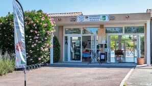 En bygning med et skilt, der viser 'La Guinguette des Demeures', og en tydelig indgang med glasdøre.