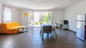 En moderne stue med sofa, spisebord, stole, fjernsyn og køleskab.