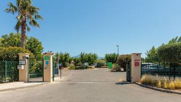 A gated entrance with a palm tree, a clear sky, and a mountain in the background.
