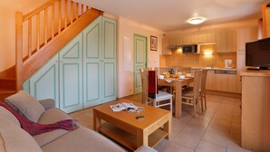 Uma sala de estar com sofá, mesa de centro de madeira e escada com portas verdes.
