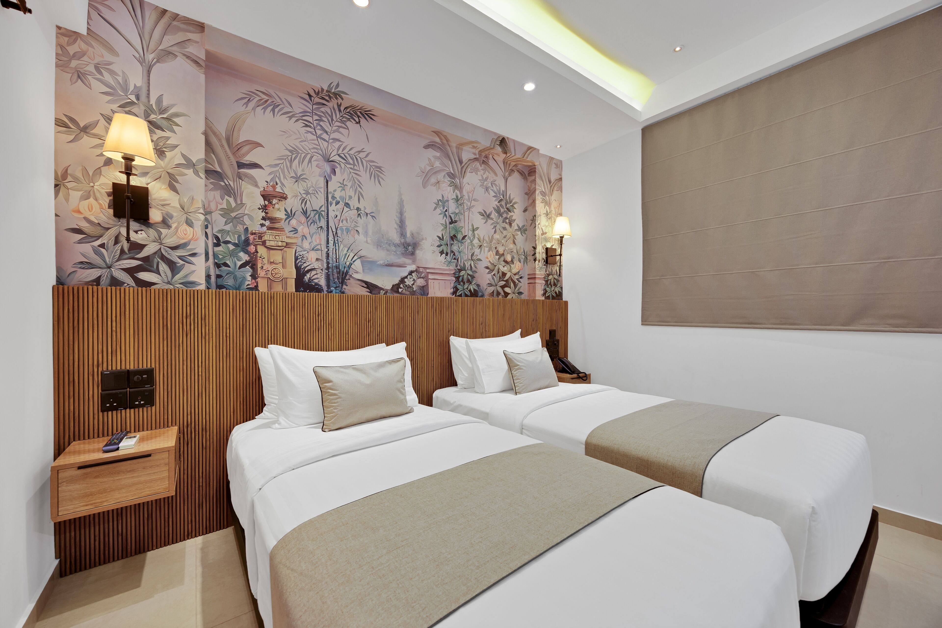 A hotel room with two beds, a wooden headboard, a mural, and a nightstand with a lamp.