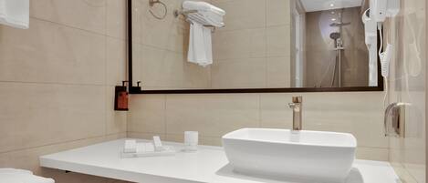 A modern bathroom with a large mirror, white sink, and towel rack.