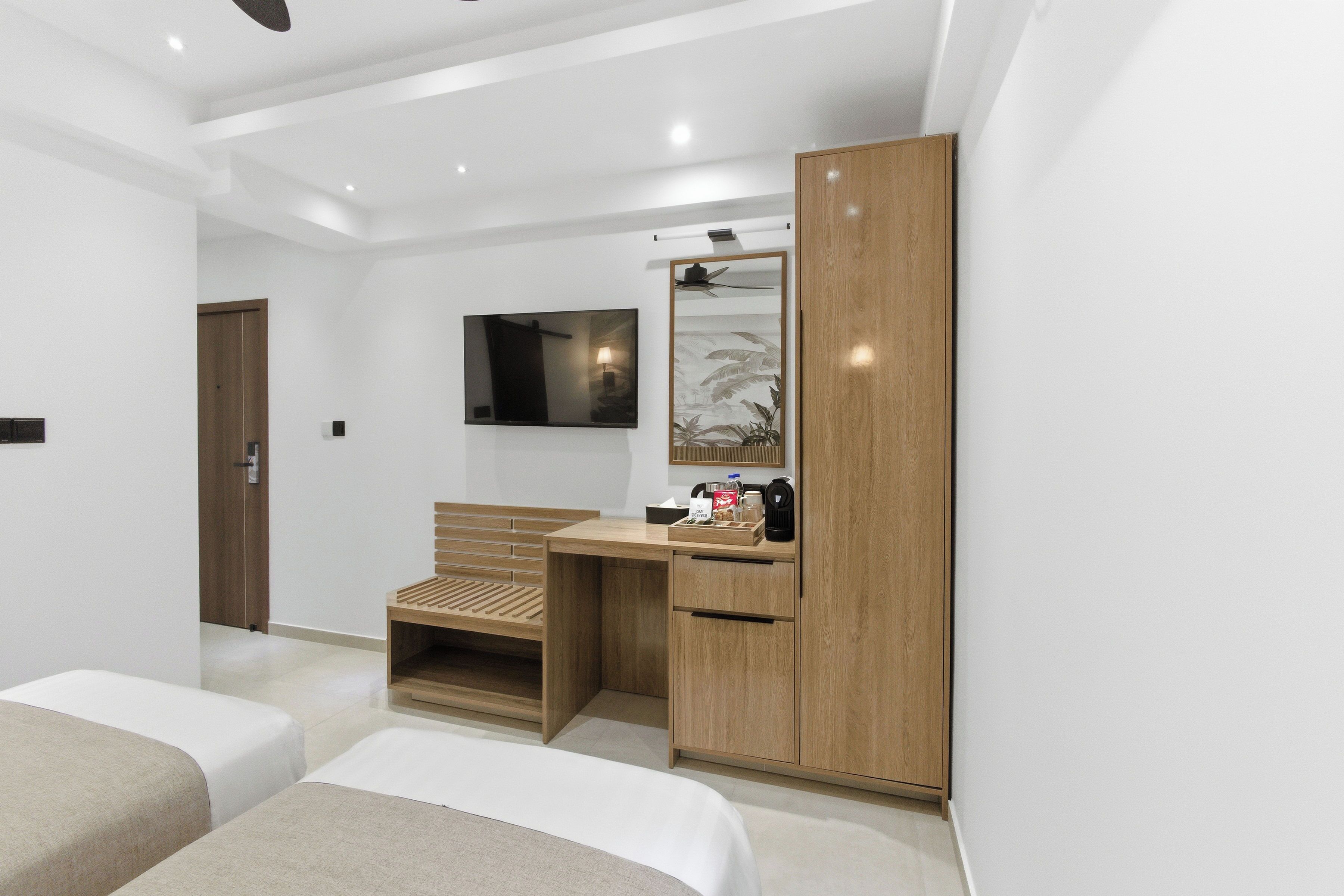 Une chambre d’hôtel équipée d’un lit, d’un bureau, d’une armoire et d’un téléviseur fixé au mur.