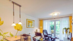 Uma sala de estar moderna com área de jantar, um sofá, uma poltrona e uma mesa.