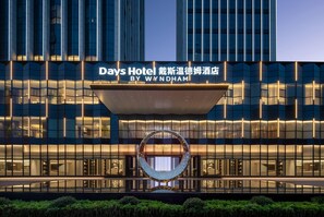 A hotel building with a modern facade, a large illuminated sign, and a distinctive circular sculpture in front.