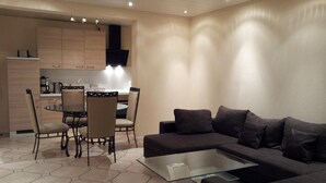 Ein modernes Wohnzimmer mit einem dunkelbraunen Sofa, einem Glastisch und einem hexagon-gefliesen Boden.