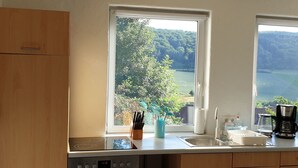 Eine Küche mit großem Fenster, Backofen, Spüle und Kaffeemaschine.
