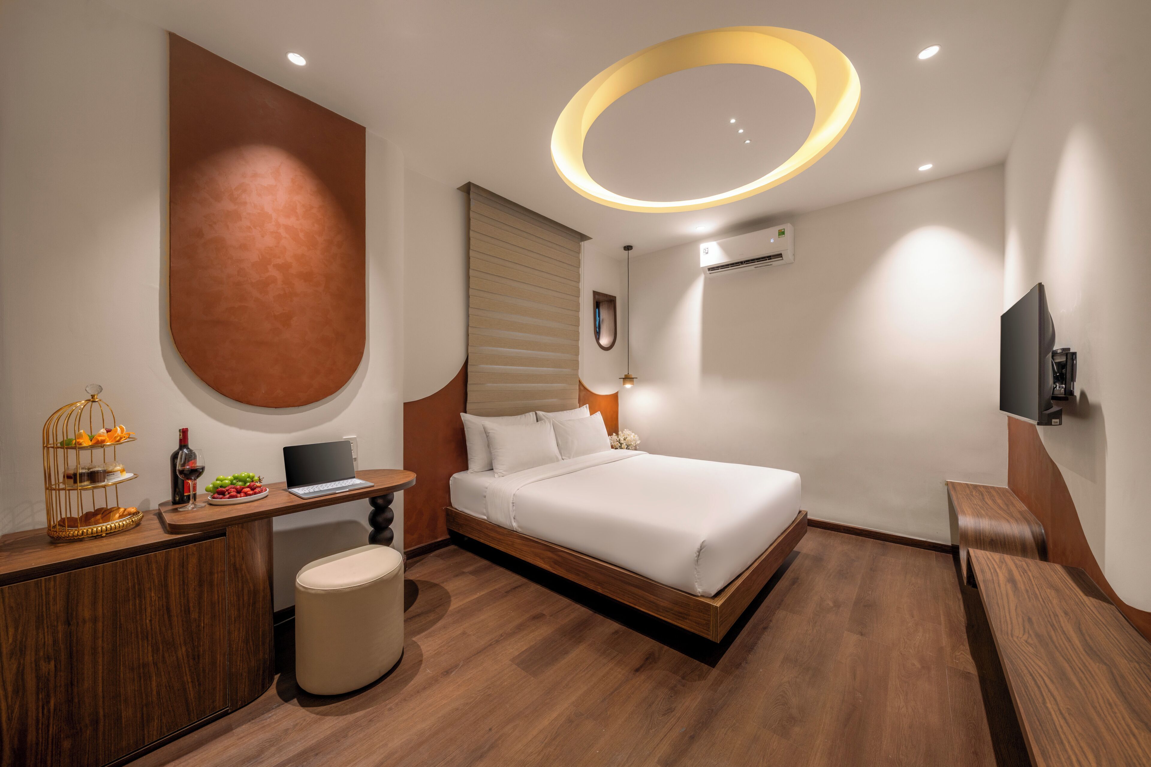 A modern hotel room with a bed, desk, and seating area.