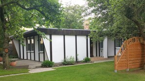 Een modern huis met een witte gevel, zwarte accenten en een houten poort.