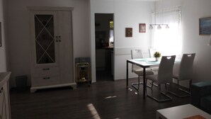 Een eethoek met een tafel en stoelen, een kast met glazen deuren, en een keuken op de achtergrond.
