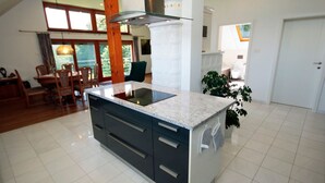 Una cucina moderna con isola centrale, zona pranzo con sedie di legno e un'ampia finestra che offre luce naturale.