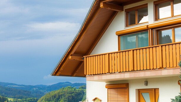 Un edificio a due piani con un balcone, ampie finestre e vista sul paesaggio circostante.