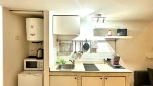 Una cocina compacta con microondas, lavamanos y armarios.