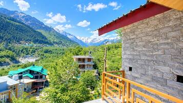 A mountain view with a stone building and a green-roofed structure.