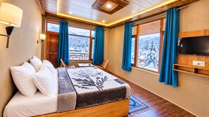 Habitación de hotel con cama, televisión y vista a árboles nevados.