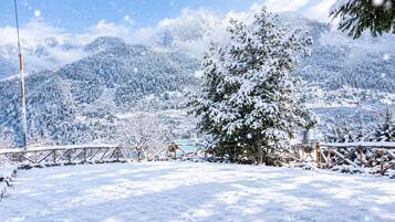 A snow-covered landscape with a wooden fence and a tree in the foreground.
