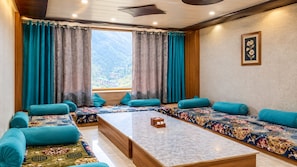 Ein Zimmer mit einer Sofagarnitur, einem Couchtisch und Bergblick durch ein Fenster.